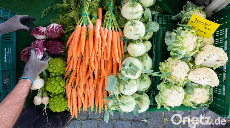 Ein Händler sortiert frisches Gemüse an seinem Verkaufsstand auf einem Wochenmarkt. Die Verbraucherpreise für frische Nahrungsmittel liegen in diesem April fast zehn Prozent über dem Vorjahresniveau. Bild: Julian Stratenschulte/dpa