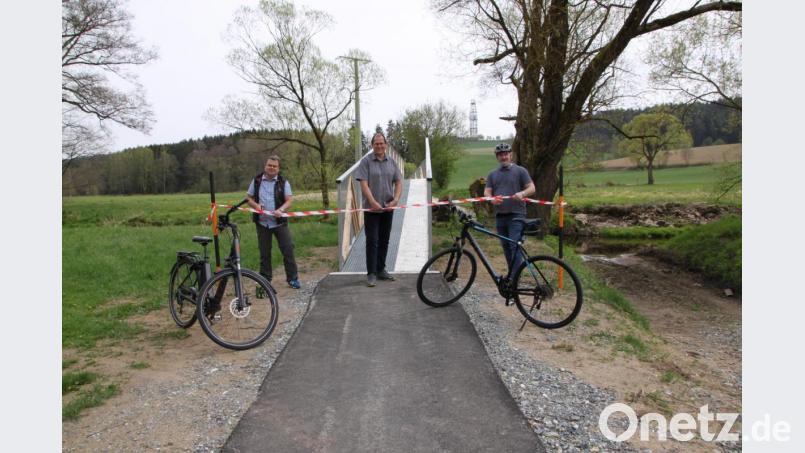 Der Windischeschenbacher Bürgermeister Karlheinz Budnik (links) kam mit einem E-Bike, das bei der Stadt auch ausgeliehen werden kann. Der scheidende Krummennaaber Rathauschef Uli Roth (rechts) trat traditionell in die Pedale. Karsten Heßing, Mitarbeiter im Amt für Ländliche Entwicklung in Tirschenreuth und Vorstand der Teilnehmergemeinschaft Steinwald, durchschnitt das Band für die neue Radbrücke in Trautenberg (im Hintergrund der Turm der KTB). Bild: den