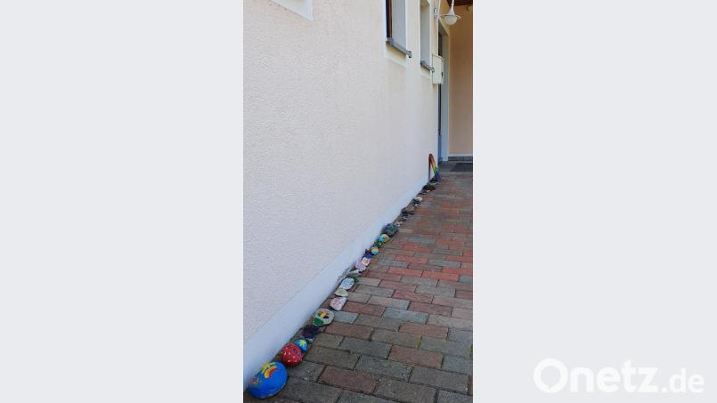 Bei der Eingangstür zum Kindergarten beginnt die Schlange aus bunt bemalten Steinen. Bild: hl