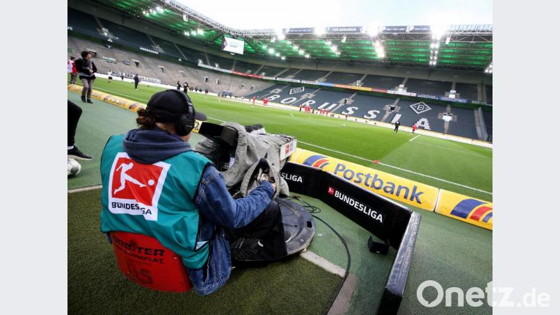 Ein Kameramann filmt das Aufwärmen der Mannschaften aus Gladbach und Köln im zuschauerfreien Stadion Borussia-Park. Das Spiel fand wegen des Coronavirus ohne Zuschauer als Geisterspiel statt. Bild: Roland Weihrauch/dpa