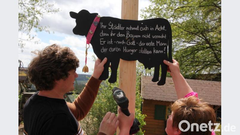 Florian und Gabi Schmidkonz bringen das Spruchschild am Maibaum an. Bild: kro