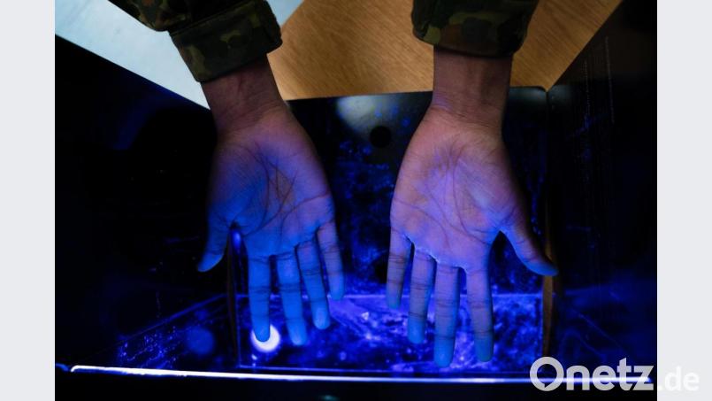 Ein Soldat kontrolliert mit Hilfe von UV-Licht die korrekte Händedesinfizierung. Bild: Nicolas Armer/dpa