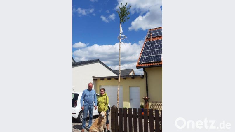 Dieter Hahn mit Gattin Nadiya und Hund vor ihrem Maibaum, der den Zusammenhalt der Siedlerfamilie Krumme Äcker symbolisieren soll. Bild: Kunz