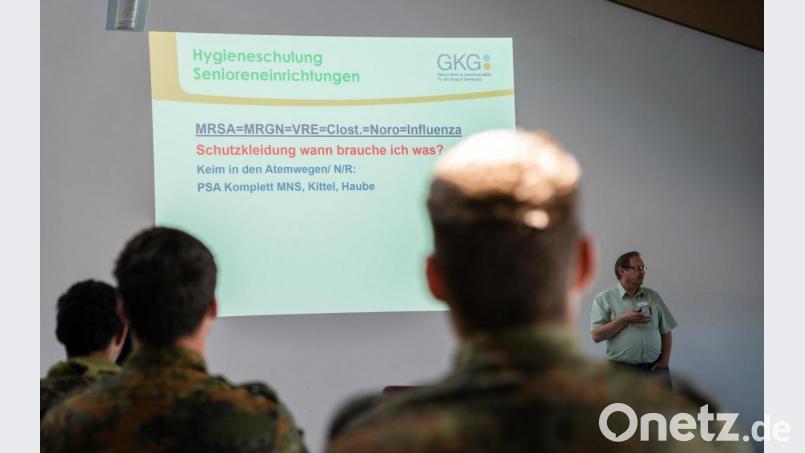 Die Hygienefachkraft der Gemeinnützigen Krankenhausgesellschaft (GKG) Bamberg, Andreas Schnell, unterweist die neu angekommenen Soldaten in Hygienemaßnahmen in Pflegeeinrichtungen. Bild: Nicolas Armer/dpa