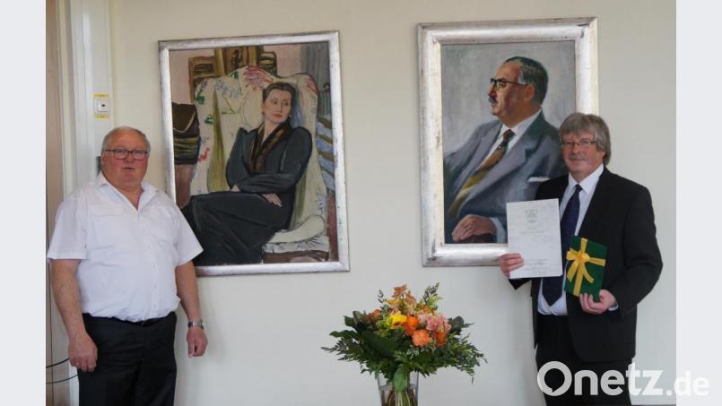 Vor den Portraits des Ehepaars Max und Margret Schwarz, deren Vermächtnis im Arbeitsleben von Wolfgang Ruhland (rechts) eine tragende Rolle spielt, überreichte Bürgermeister Weigl die Urkunde zum Dienstjubiläum. Bild: weu