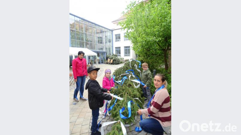 Drei Kindergartenkinder aus dem Marienheim schmücken mit ihren Erzieherinnen den Maibaum. Bild: Daniela Donhauser