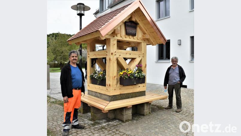 Gemeindearbeiter Manfred Luber (links) und der Vorsitzende des Gartenbauvereins Illschwang, Lorenz Geitner, stehen zufrieden am neu gestalteten Dorfbrunnen neben dem Rathaus. Bild: no