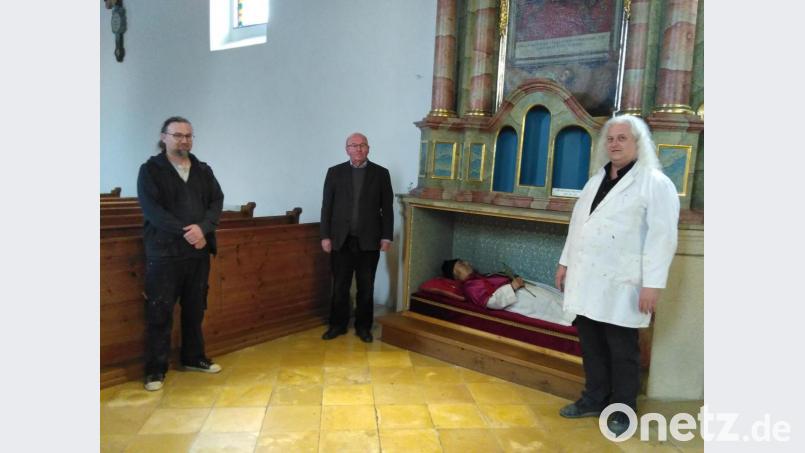 Pfarrer Wilhelm Bauer (Mitte) freut sich, dass die Nepomukfigur, welche die Bekleidung eines Domvikars trägt, wieder an Ort und Stelle ist. Ernst Dietmar Feldmann (rechts) und Stefan Gruber (links) haben die Restaurierung durchgeführt. Bild: rfi