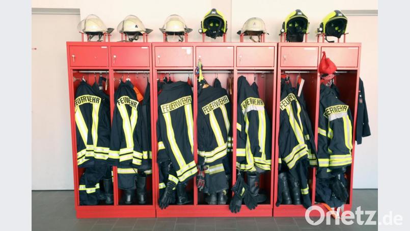 Jacken und Helme der Feuerwehr hängen in einem Schrank. Symbolbild: Bernd Wüstneck/Dpa