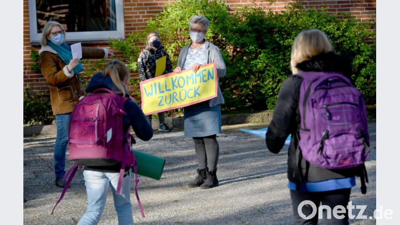 Mit einem Schild "Willkommen zurück" begrüßt eine Lehrerin die Viertklässler in einer Grundschule. Schleswig-Holstein öffnet die Schulen für die 4. Klassen an Grundschulen, am Montag ist es in Bayern soweit. Bild: Carsten Rehder/dpa