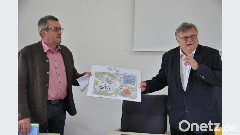 Der Personalratsvorsitzende Roland Steininger überreicht Manfred Porsch eine Collage mit Fahrradkarte und Geldscheinen für das von ihm gewünschte E-Bike. Bild: ak