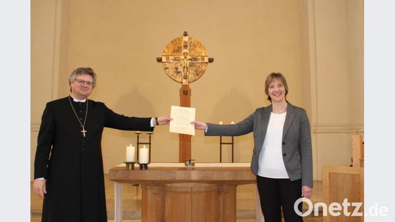 Dekan Karlhermann Schötz (links) übergibt die Urkunde an Kantorin Kerstin Schatz. Die trägt jetzt den Titel Kirchenmusikdirektorin. Bild: Veronika Fleps