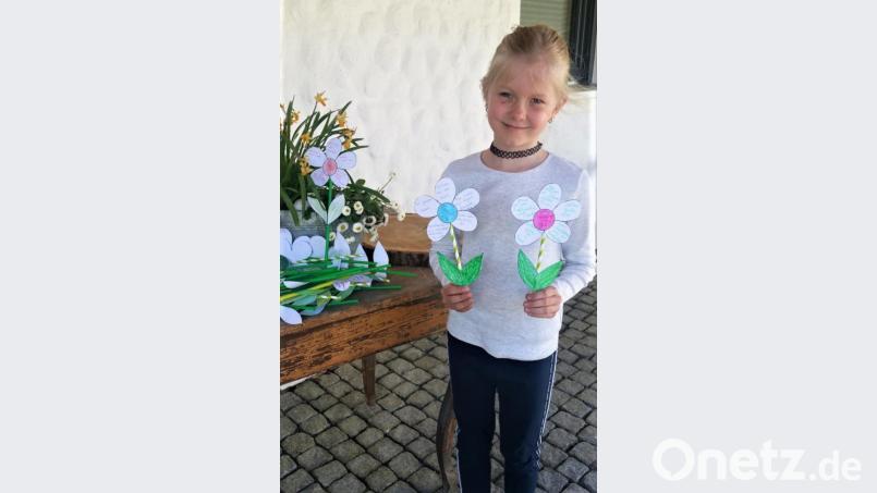 Leni zeigt stellvertretend für die rund 35 Kinder, eine kleine Auswahl der mit unterschiedlichen Farben und Sprüchen liebevoll gebastelten Papierblumen, die dann in der Pfarreiengemeinschaft verteilt wurden. Bild: fdl