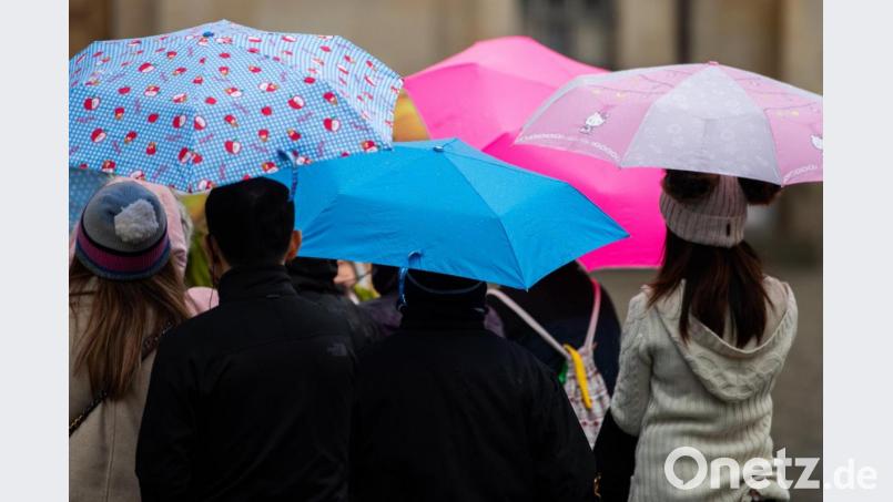 Menschen gehen mit Regenschirmen durch die Innenstadt. Symbolbild: Robert Michael/dpa