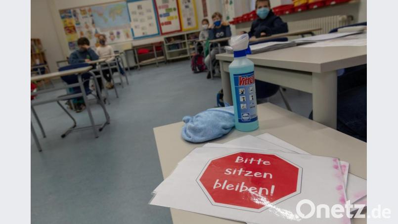 Ein Schild mit der Aufschrift &quot;Bitte sitzen bleiben!&quot; liegt auf einem Tisch im Klassenraum einer vierten Klasse. Bild: Peter Kneffel/dpa