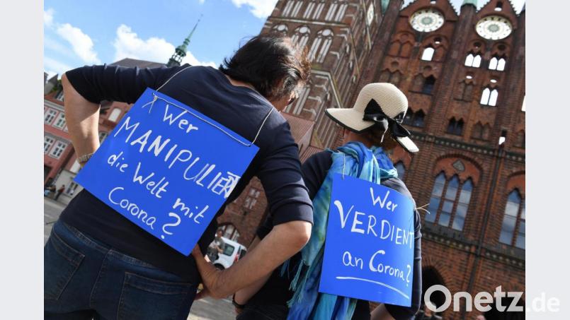 Auf einer Demonstration gegen die Maßnahmen zur Eindämmung der Corona-Pandemie tragen zwei Frauen Schilder mit den Aufschriften: &quot;Wer manipuliert die Welt mit Corona?&quot; und &quot;Wer verdient an Corona?&quot; Bild: Stefan Sauer/dpa
