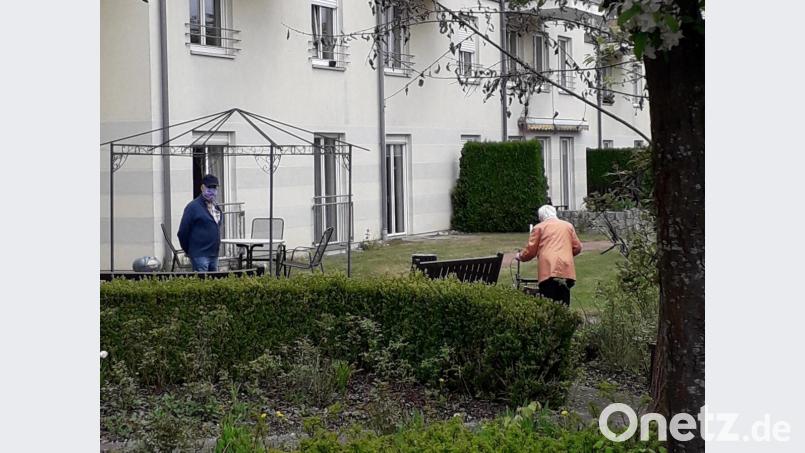 Mit Maske und Rollator sind Bewohner des Kastenbauer-Hauses im blühenden Garten unterwegs. Bild: hka