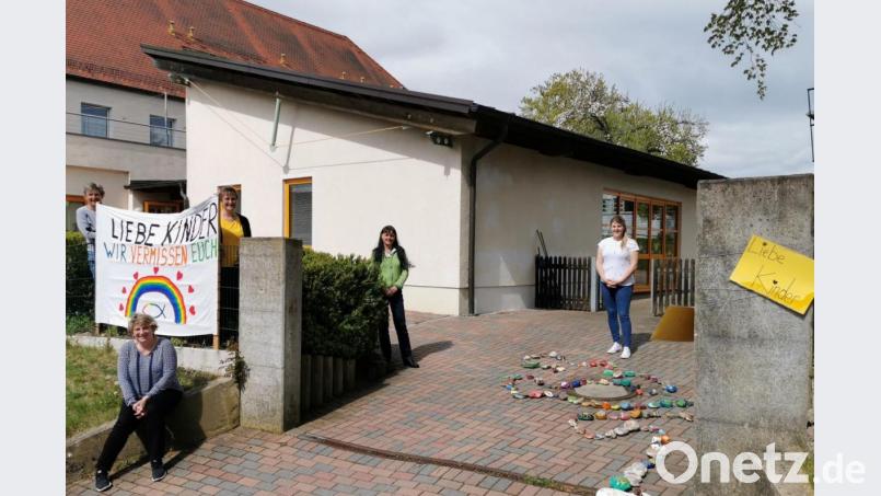 Mit einem bunten Banner und einer Steinschlange wartet das Kindergartenpersonal auf die Kinder. Bild: gz