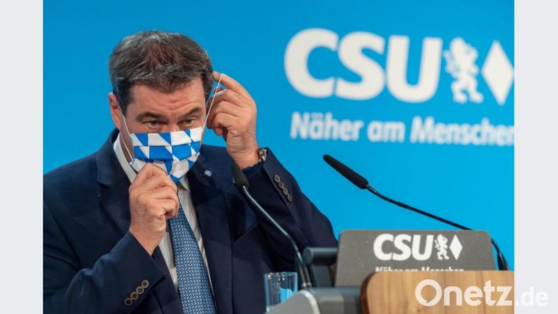 Markus Söder (CSU) steht auf einem Podium und setzt sich seine Mundschutzmaske auf. Foto: Peter Kneffel/dpa Bild: Peter Kneffel