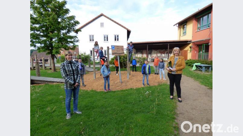 Ein Erinnerungsfoto im Pausenhof: Rektorin Ortrud Sperl, die Grundschüler und Elternbeiratsvorsitzende Erika Biegerl bewundern das neue Schild für den Autoparkplatz. Bild: dis