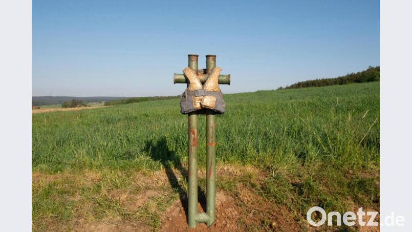 Eine in Blei abgeformte, vergoldete Kinderschwimmweste „hängt“ über einem Stahlrohrkreuz, an dem normalerweise Fähren vertäut werden. Bild: Wilhelm Koch