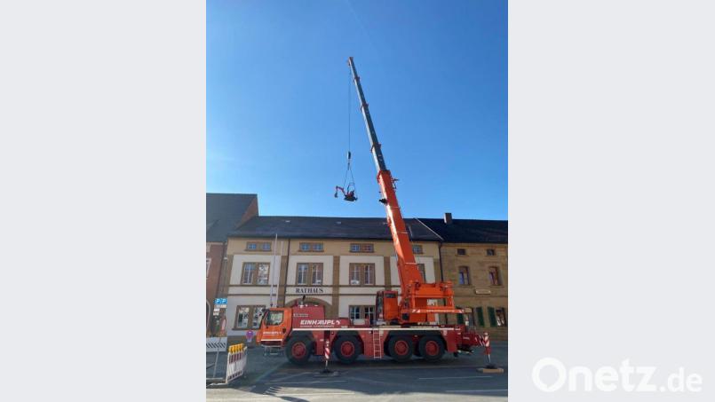 Am wolkenlosen Himmel schwebt der Minibagger über dem Vilsecker Rathaus. Bild: Stefanie Gradl