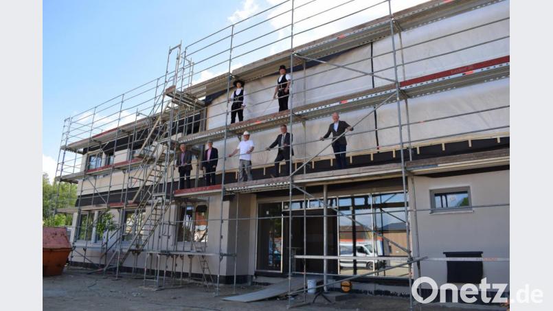 Richtfest nach nur 14 Tagen Bau: Die Zimmerleute (oben) und Günther Meyer (unten Mitte) von Regnauer Fertighaus sowie Kewog-Geschäftsführer Bernd Büsching (rechts) freuen sich über den raschen Baufortschritt am neuen Verwaltungsgebäude. Bild: szl