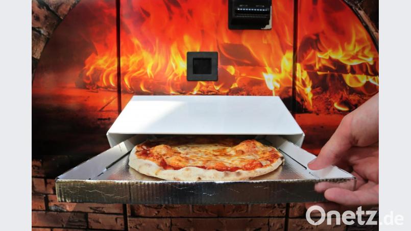 Ein Kunde greift nach einer Pizza Margherita die nach etwa drei Minuten Backzeit aus einem Automaten ausgeworfen wird. Foto: Karl-Josef Hildenbrand/dpa Bild: Karl-Josef Hildenbrand