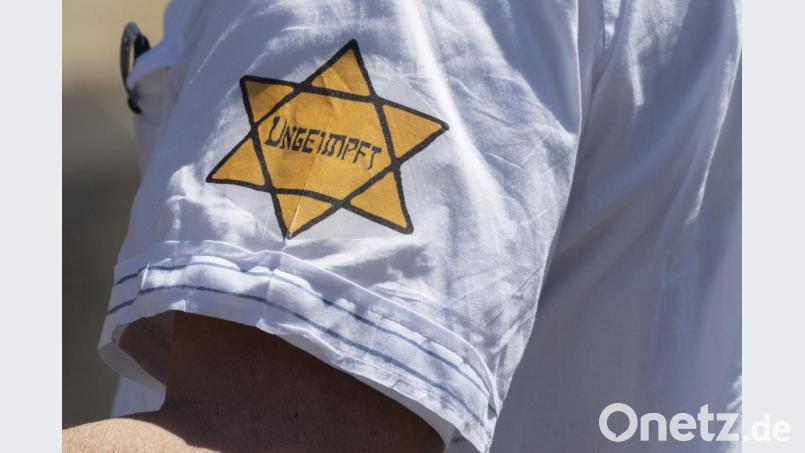 „Ungeimpft“ steht auf einem nachgebildeten Judenstern am Arm eines Mannes. Bild: Boris Roessler/dpa