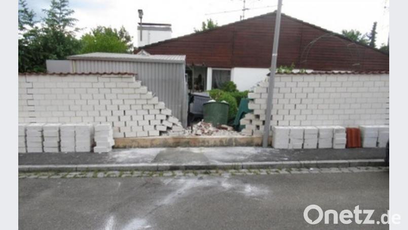 Die Wucht des Aufpralls war so groß, dass dabei nicht nur ein Loch in die Gartenmauer des Nachbarn gerissen wurde, sondern auch ein Schuppen und ein Gewächshaus dahinter beschädigt wurden. Bild: Polizei Amberg