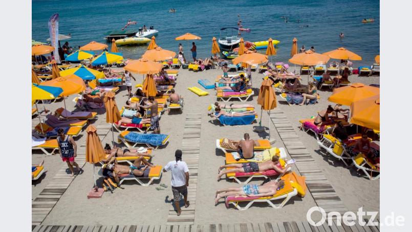 Touristen genießen die Sonne an einem Strand nahe der Stadt Kos auf der gleichnamigen griechischen Insel. Archivbild: Santi Palacios/dpa