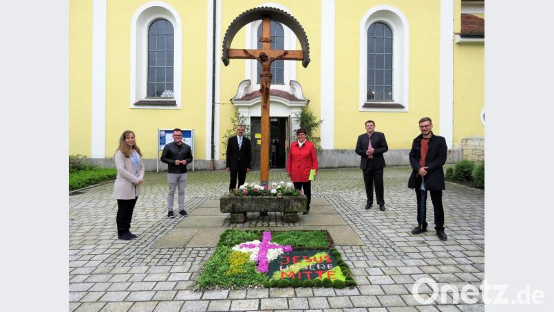 Pfarrer Martin Besold und Gemeindereferentin Roswitha Heining (links und rechts neben dem Kreuz) mit einigen Gläubigen beim Blumenteppich der Kommunionkinder-Familien Mihl und Beierl kurz vor dem Fronleichnams-Gottesdienst. Bild: ubb
