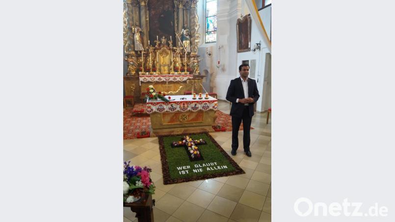 "Wer glaubt, ist nie allein" stand auf dem Blumenteppich, den Pfarrer Pater Anish George am Altar bewunderte. Bild: soj