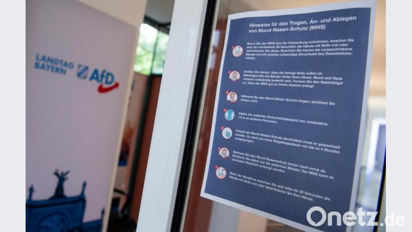 Eine Infotafel für das Tragen, An- und Ablegen von Mund-Nasen-Schutz hängt an einer Tür des bayerischen Landtags. Bild: Sven Hoppe/dpa