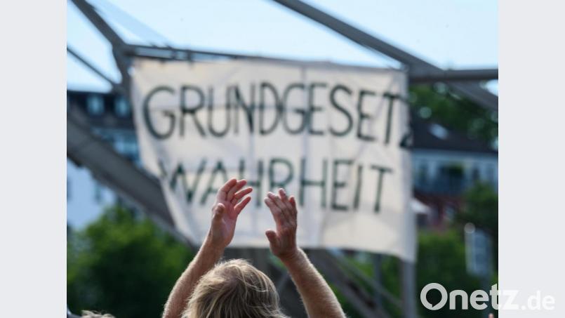 Ein Demonstrant klatscht vor einem Plakat mit dem Slogan «Grundgesetz Wahrheit». Bild: Andreas Arnold/dpa