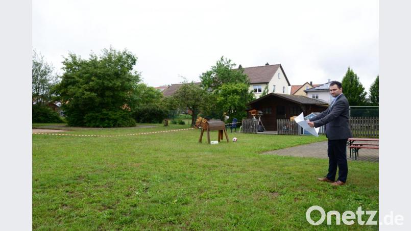 Im Bereich der linken Baum- und Buschgruppe soll der Neubau errichtet werden. Bürgermeister Sebastian Hartl macht sich vor der Marktgemeinderatssitzung nochmal ein genaues Bild von der Örtlichkeit. Die Terrasse (im Hintergrund mit der Sitzbank) soll überdacht werden, außerdem wird in diesem Bereich der Verbindungsgang zum bestehenden Kinderhaus errichtet. Bild: bey