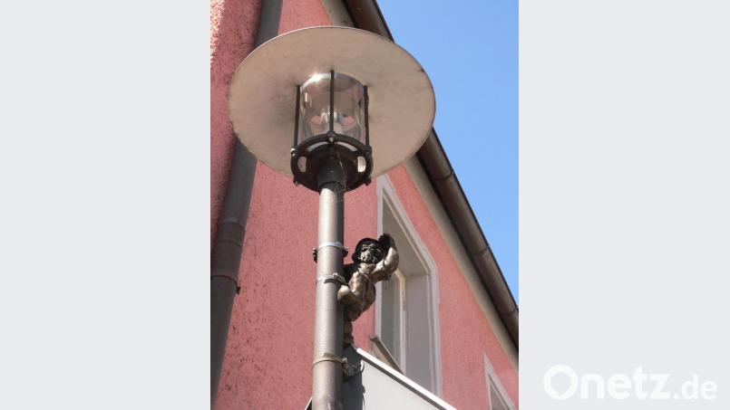 Von einer Straßenlampe schaut ein Bronzezwerg auf den Marktplatz von Luhe. Bild: mh