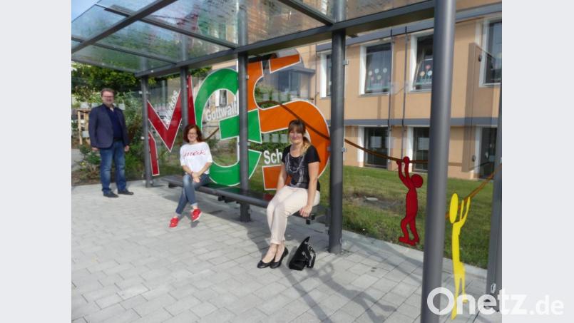 Rektor Wolfgang Bodensteiner und Konrektorin Anja Bräu (von links.) sind begeistert von der Arbeit Claudia Heindls. Ein bunter Schriftzug verschönert die Glasscheibe der Bushaltestelle vor der Markus-Gottwald-Schule. Bild: rn