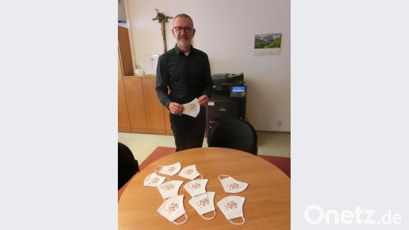 Stadtpfarrer Thomas Vogl mit den Restexemplaren der besonderen Mund-Nase-Bedeckungen, die noch im Pfarrbüro erhältlich sind. Bild: kgg