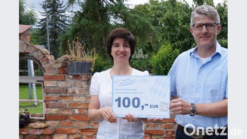Kreisbäuerin Sabine Schindler überreicht einen der 100-Euro-Gutscheine an Wolfgang Pirzer, den stellvertretenden Kreisvorsitzenden des Hotel- und Gaststättenverbandes. Bild: J. Wittmann/exb