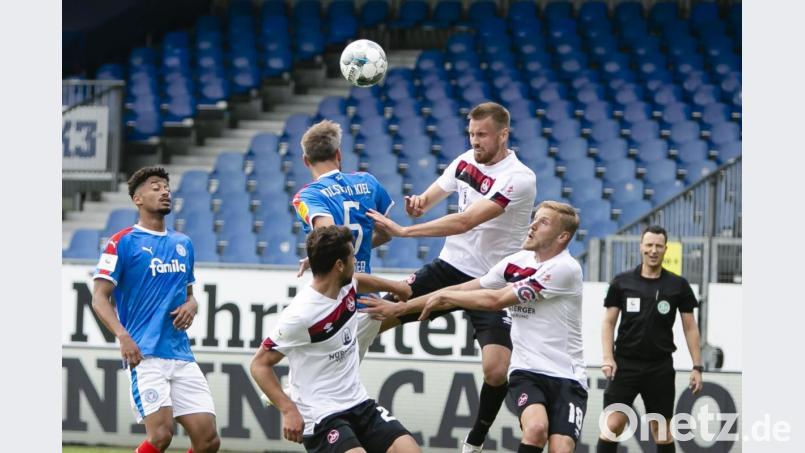 Kiels Stefan Thesker (Zweiter von links), Nürnbergs Asger Sörensen und Nürnbergs Hanno Behrens versuchen an den Ball zu kommen. Trotz eines 1:1 muss der 1. FCN in die Relegation. Bild: Frank Molter/dpa