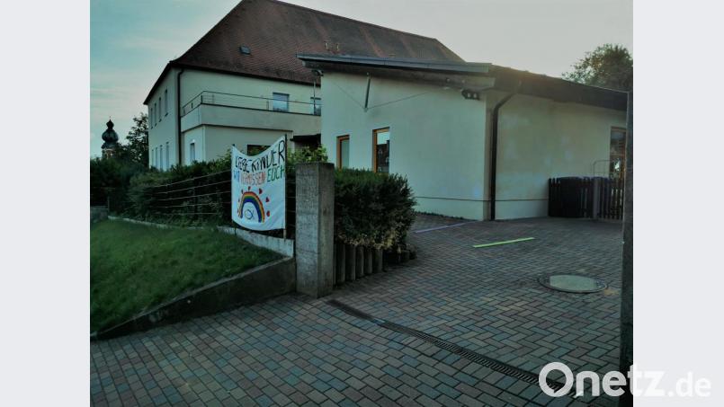Mit einem großen Leinentuch mit der Aufschrift „Liebe Kinder wir vermissen Euch“ begrüßt das Kindergartenteam die Kinder. Bild: gz