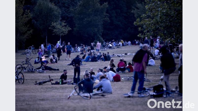 Menschen sitzen nachts im Volkspark Hasenheide auf einer Wiese. Bild: Christoph Soeder/dpa