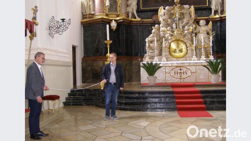 Stadtpfarrer Thomas Vogl (links) und Kirchenmusikdirektor Andreas Sagstetter halten vorm Hochaltar in der Basilika jeweils an den Enden einen Zwei-Meter-Stab. So viel Abstand müssen die Chorsänger voneinander einhalten. Bild: pz