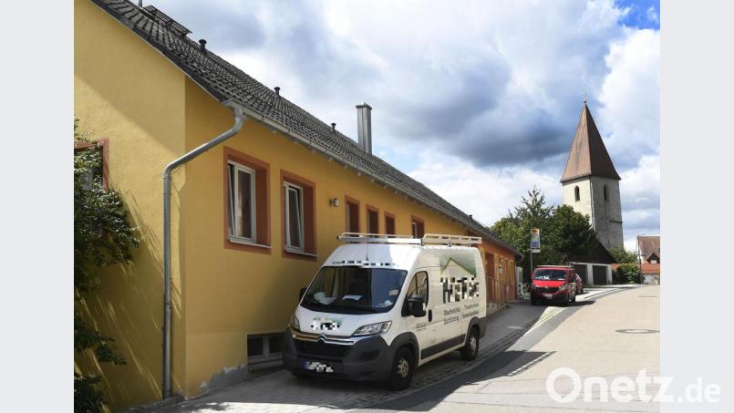 Fahrzeuge von Bauunternehmen vor der ehemaligen Raiffeisenfiliale in Ammerthal. Um die Bauarbeiten gibt es Streit im Gemeinderat. Bild: Petra Hartl