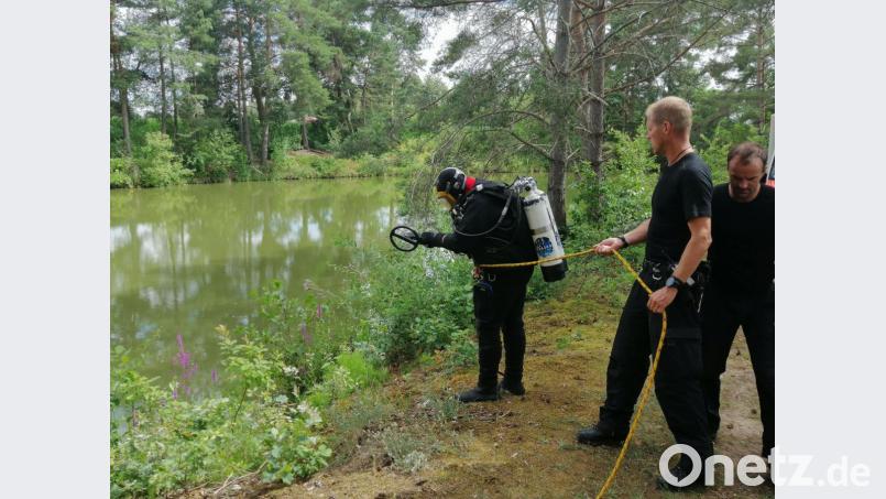 Der Taucher der Bereitschaftspolizei ist kurz davor, den kleineren der beiden Weiher in der Nähe des Tatorts in Büchelkühn, nach der Tatwaffe abzusuchen.Seine Kollegen sichern ihn. Bild: wpt