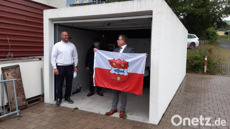 Im Freibad soll künftig die Windischeschenbacher Fahne wehen. Bürgermeister Karlheinz Budnik überreicht Bademeister Horst Lindner die Flagge in den Stadtfarben. Bild: Lowak