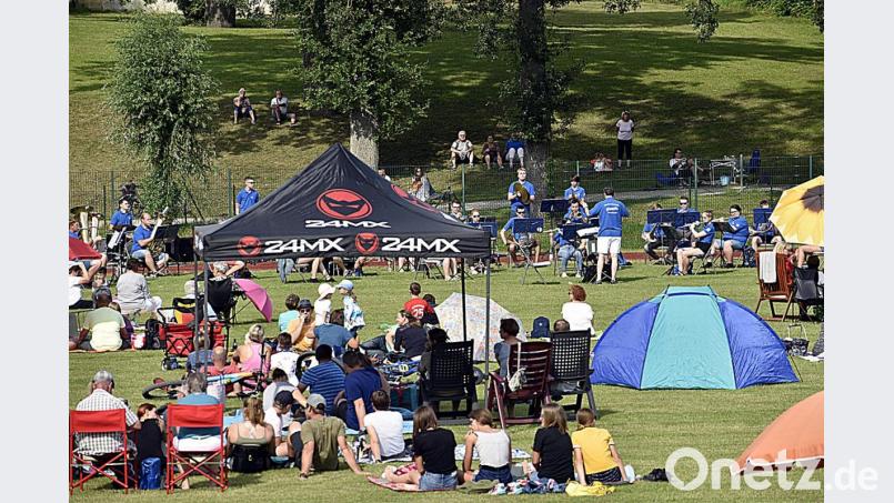 Den gebotenen Abstand wahren die Auerbacher, als sie es sich zum Blasmusik-Picknick auf dem Schulsportplatz gemütlich machen. Bild: sck