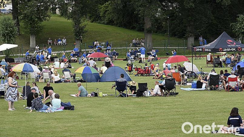 Den gebotenen Abstand wahren die Auerbacher, als sie es sich zum Blasmusik-Picknick auf dem Schulsportplatz gemütlich machen. Bild: sck