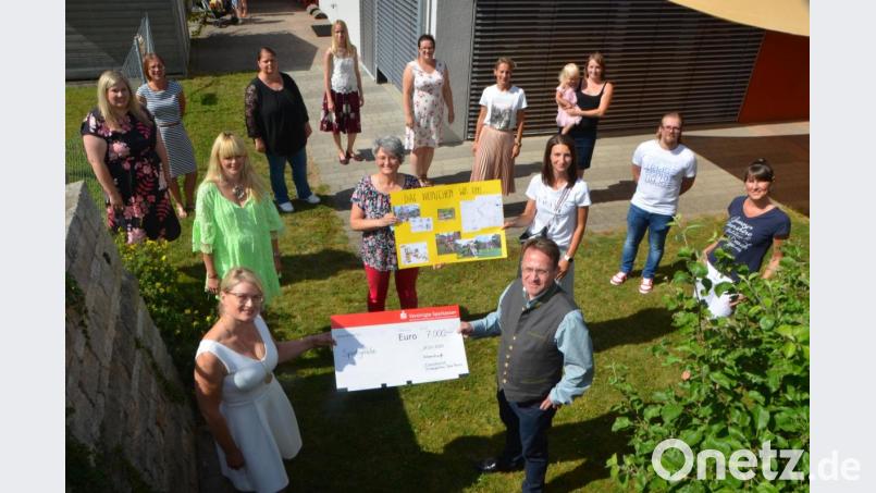 Elternbeiratsvorsitzende Heidi Sollfrank (vorne, links) überreicht den 7000-Euro-Spendenscheck nach der Schlussandacht im Beisein ihres Teams an Dekan Alexander Hösl (vorne, rechts). Das Geld wird im Garten für ein Spielgerät ausgegeben. Bild: dob